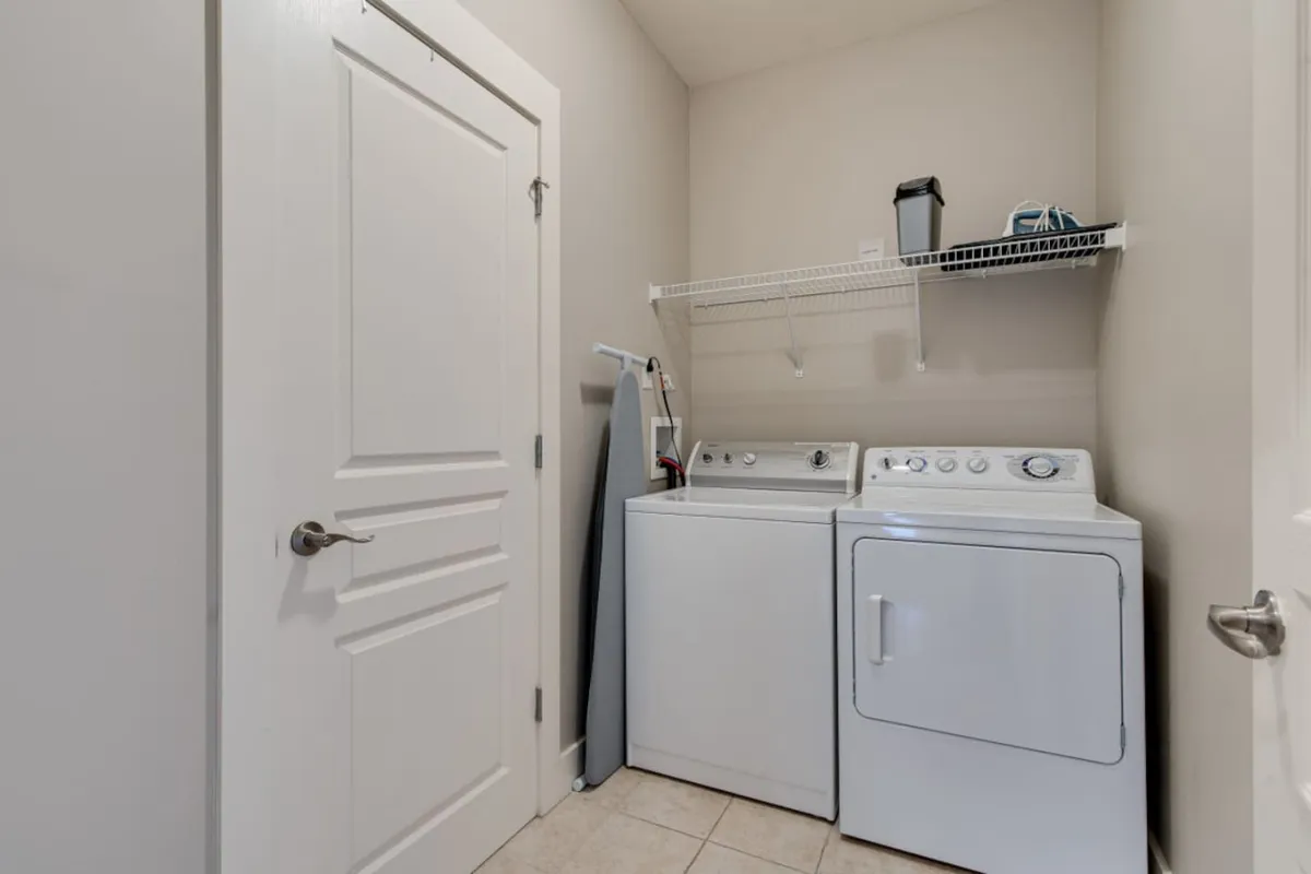 A laundry area with washer, dryer, shelving, and ironing equipment, emphasizing practicality and convenience for longer stays or after active days exploring the city.