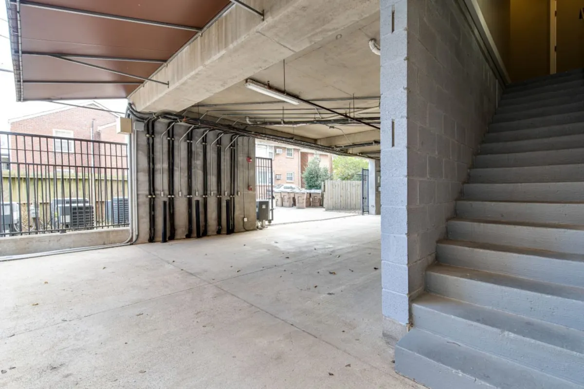 This image provides an interior view of the garage, featuring a visible staircase leading directly into the living space, open garage area suitable for two vehicles, and sturdy support beams. The layout suggests ample space for parking and storage, as well as seamless, private access to the home.