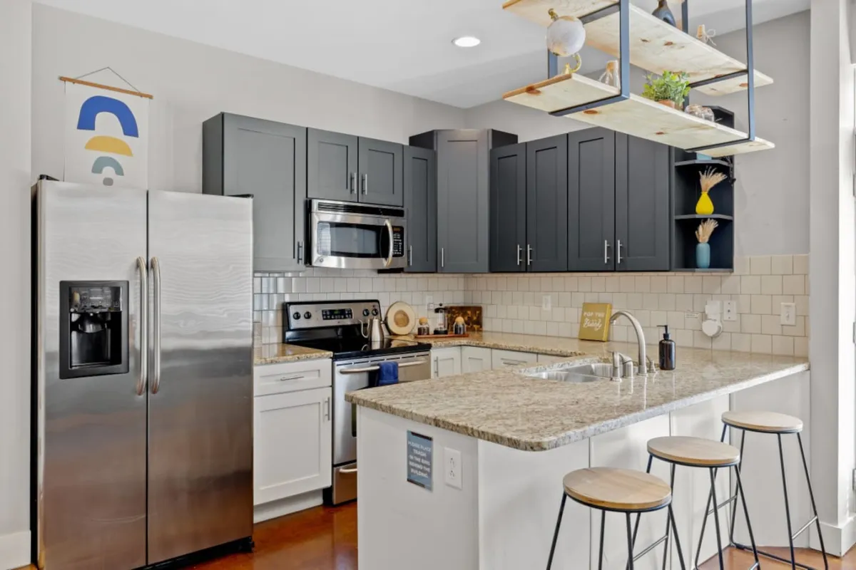 A welcoming, spacious kitchen featuring granite countertops, stainless steel appliances, and open shelving. The scene suggests an inviting atmosphere for family cooking and casual gatherings.